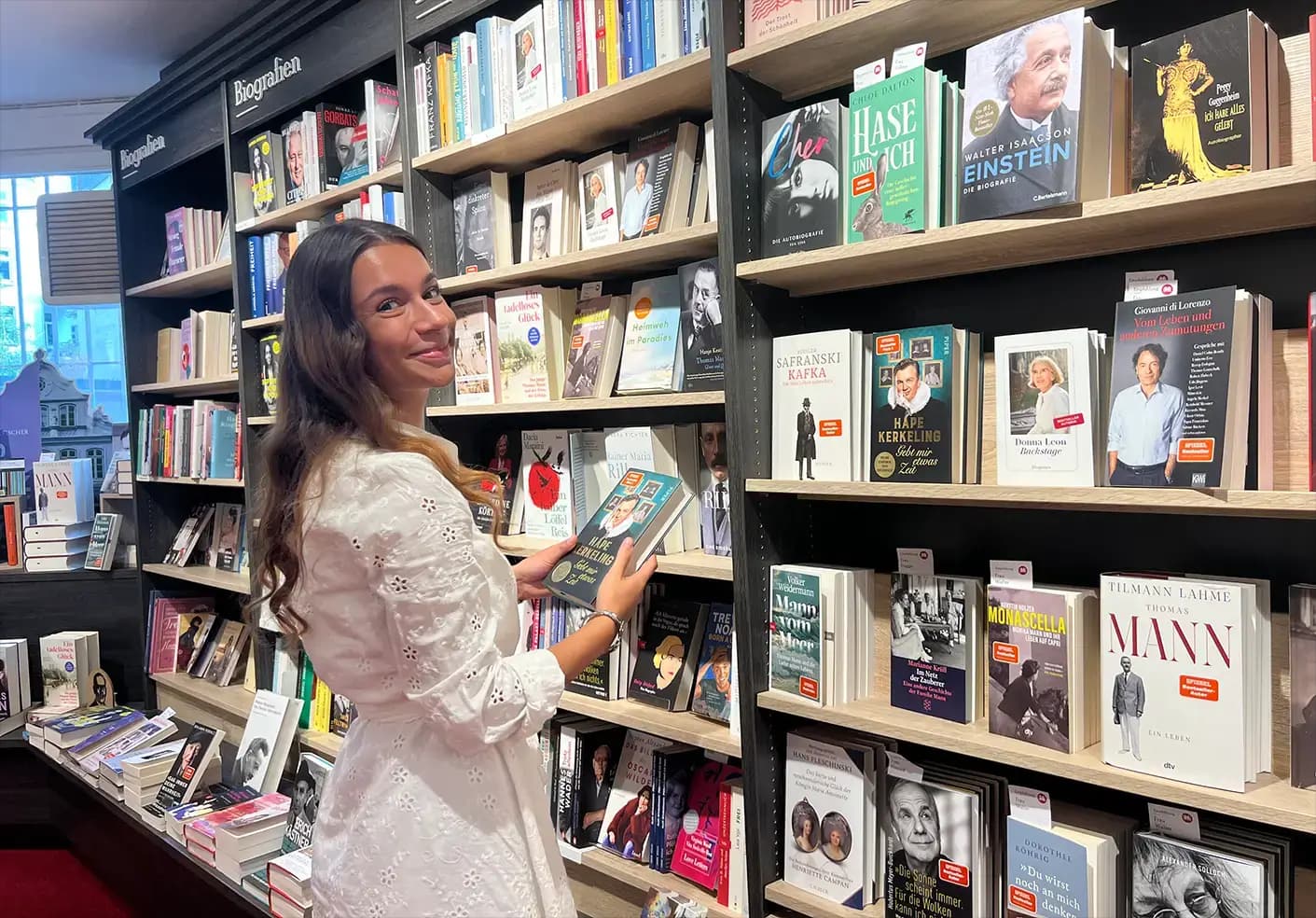 Eine Heymann-Kollegin sortiert Bücher in ein Bücherregal ein.