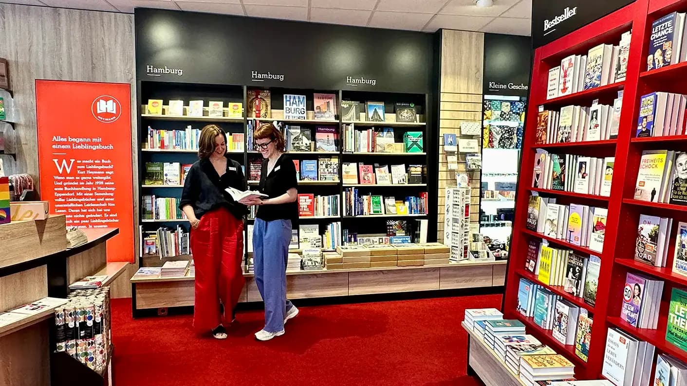Zwei Heymann-Kolleginnen unterhalten sich in einer hellen, freundlichen Buchhandlung.