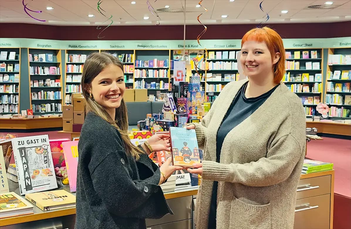 Zwei Heymann-Kolleginnen präsentieren ein Kinderbuch in die Kamera.